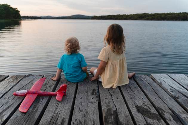 Creative Highlights Symbolbilder Brother and sister sitting on pier over lake model released, Symbolfoto, NDEF01760