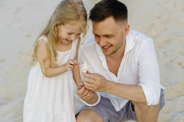 Happy father showing shell to daughter at beach model released, Symbolfoto, NSTF00132