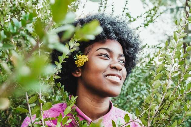 Creative Highlights Symbolbilder Smiling woman amidst green bush at park model released, Symbolfoto, PBTF00555