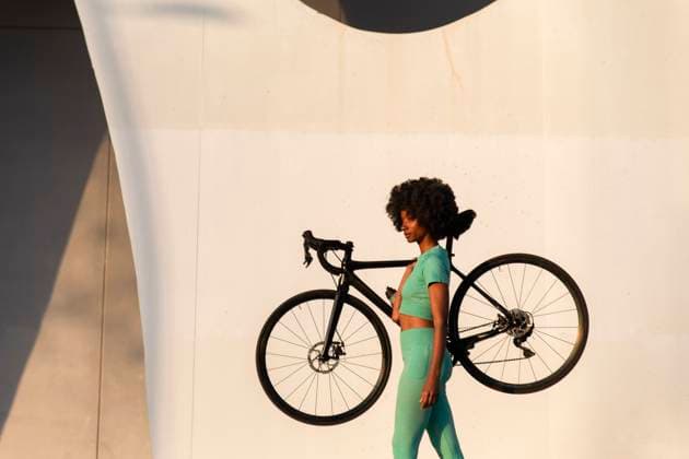 Creative Highlights Symbolbilder Mature woman carrying bicycle by white wall model released, Symbolfoto, PCLF01095