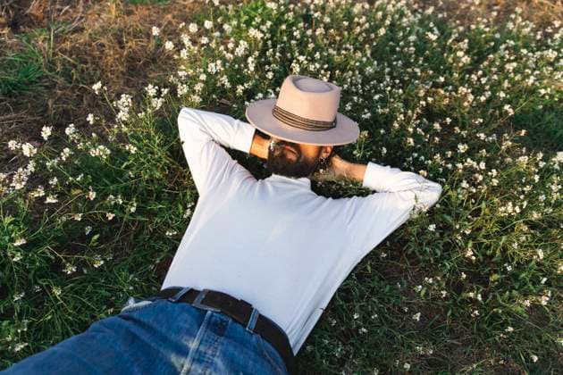 Creative Highlights Symbolbilder Man covering face with hat and lying on flowering plants model released, Symbolfoto, PCLF01111