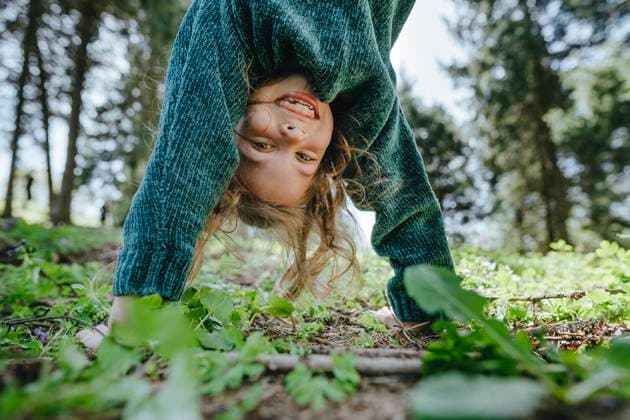 Creative Highlights Symbolbilder Smiling girl doing handstand in forest model released, Symbolfoto, YTF02234