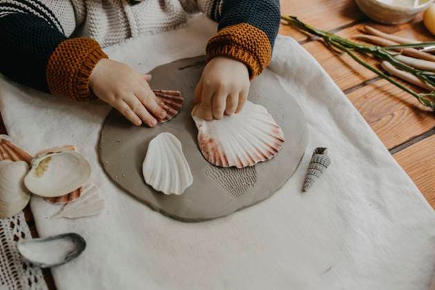 Boy making seashell imprint on clay at home model released, Symbolfoto property released, MCHF00100