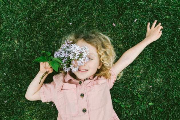 Creative Highlights Symbolbilder Smiling girl lying on grass with lilac flowers at park model released, Symbolfoto, SIF01121