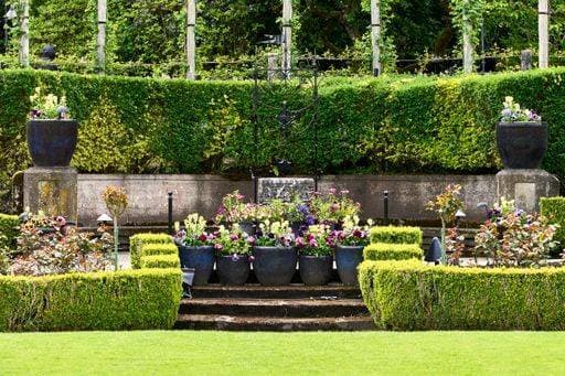 Green lawn leading to cement steps and colorful spring tulips in large pots at Butchart Gardens. Victoria, BC. 24604945