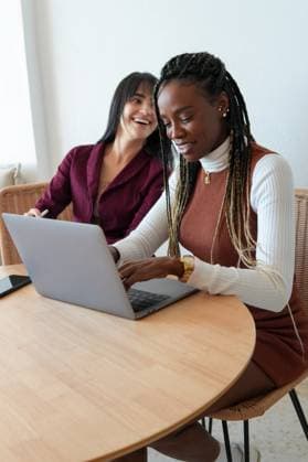 Creative Highlights Symbolbilder A cheerful scene of two diverse women working together on a laptop in a well-lit home environment, engaging in what appears to be a collaborative project or discussion Model Released OscarDeDios_ID21713_636951_014 Copyright: xOscarxDexDiosx