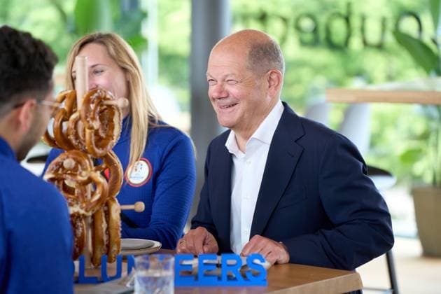 Bundeskanzler Olaf Scholz besucht den Olympiapark in München, Bayern anlässlich zur UEFA EURO 2024. Der Kanzler tauscht sich mit Helfern rund um die Fußball Europameisterschaft am Tisch mit bayerischen Brezeln aus