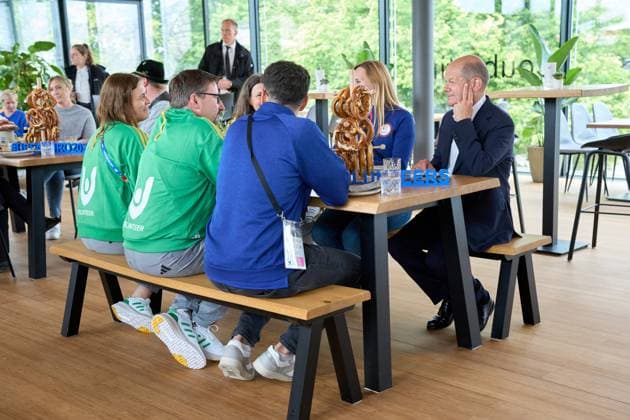 Bundeskanzler Olaf Scholz besucht den Olympiapark in München, Bayern anlässlich zur UEFA EURO 2024. Der Kanzler tauscht sich mit Helfern rund um die Fußball Europameisterschaft am Tisch mit bayerischen Brezeln aus