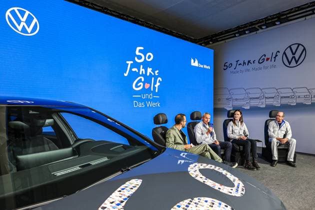Festakt 50 Jahre Golf Produktion bei Volkswagen in Wolfsburg Festakt 50 Jahre Golf Produktion, Talkrunde: Jesko Giessen, Moderator, Dr. Rainer Fessel, VW Werkleiter Wolfsburg, zwei VW-Mitarbeitende, Vordergrund: VW Golf VIII Wolfsburg VW Werk Wolfsburg Niedersachsen Germany