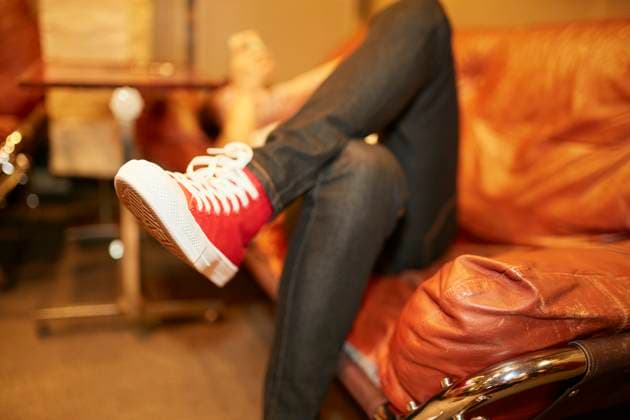 IMAGO Creative, Winter, Couching A person lounging on an orange leather couch with their legs crossed wearing red sneakers and blue jeans, with a blurred background. bola01151 Copyright: xConnectxImagesx