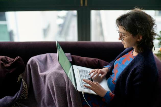 IMAGO Creative, Winter, Couching A woman sits comfortably on a purple couch with a blanket, focused on her laptop. bola01375 Copyright: xConnectxImagesx
