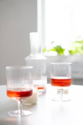 Rose wine in trendy ribbed wineglasses and decanter on white table Rose wine in trendy ribbed wineglasses and decanter on white table, weekend home wine party with candles close-up Copyright: xZoonar.com DariaxMinaevax 19465061