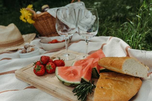 Colorful picnic with food, wine glasses, straw hat in a sunny garden Thun, Canton of Bern, Switzerland R_FFVO240607-1449588-01