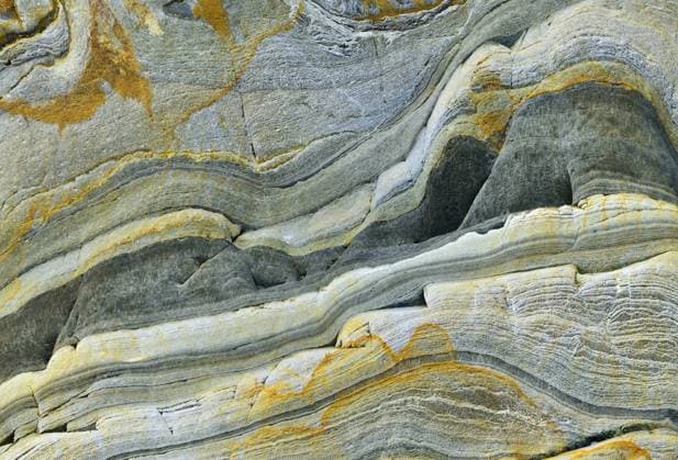 Creative Highlights World Close-up image of layered slate and quartzite rock formations displaying a stunning display of natural textures and patterns The rocks reveal a mix of gray and yellow tones formed through geological processes over centuries Model Released CesarLlaneza_ID21977_643777_012 Copyright: xCesarxLlanezax