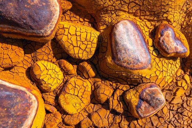 Creative Highlights World Close-up of a mineral-rich terrain featuring cracked, ochre-colored soil and large stones with varying hues Captured in the Riotinto mines of Huelva, Spain, known for its copper, gold, and silver deposits Model Released JavierMartinez_ID21971_643700_003 Copyright: xJavierxMartinezx