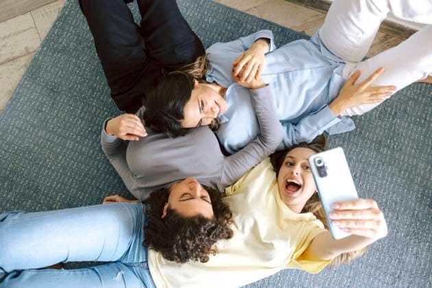 Top view of three friends lying on the floor at home, joyfully taking a group selfie, capturing a casual and cheerful moment. Model Released LuisTenza_ID21757_638163_004 Copyright: xLuisxTenzax RECORD DATE NOT STATED