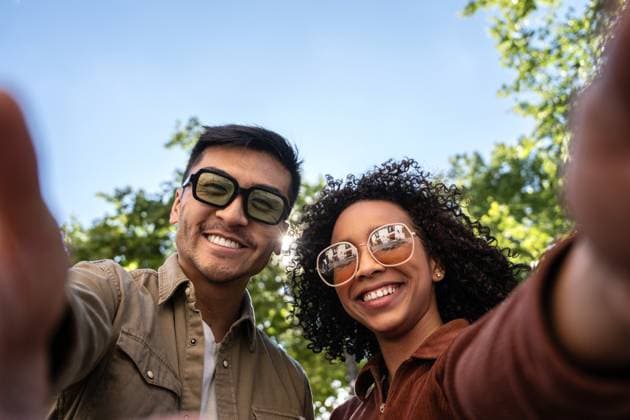 IMAGO Creative: Sommer, Sommertage im Stadtpark Multiethnic couple taking a selfie in a sunny Madrid park. The Chinese man and Hispanic woman are smiling, wearing sunglasses, and enjoying the outdoors. The background features greenery and clear blue sky. Model Released ManuelRuiz_ID21992_644068_043 Copyright: xManuelxRuizx