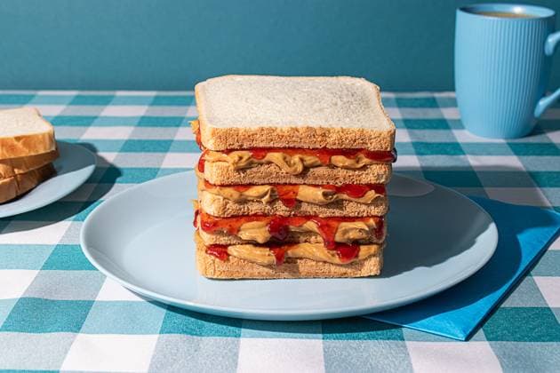 Peanut Butter and Jelly sandwich served on a blue plate , a cup of an american coffee and some bread slices in a blue background Model Released OlgaVila_ID21885_641316_003 Copyright: xOlgaxVilax
