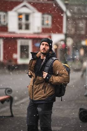 Snow gently falls around a male traveler, dressed warmly, exploring the snowy streets of a quaint town in Iceland Westman Islands, backpack in tow Model Released PabloMenendez_ID21055_620649_030 Copyright: xPabloxMenendezx