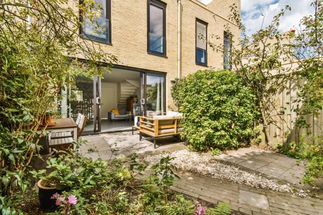 Elegant backyard patio of a modern home featuring stylish outdoor furniture, open sliding doors, and a vibrant garden. Model Released ProCreators_ID5188_167283_012 Copyright: xProxCreatorsx RECORD DATE NOT STATED