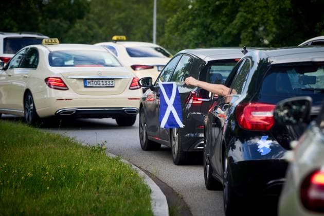 Autokorso in München zur EM 2024 bzw. Fußball-Europameisterschaft. Schottischer Fan hält eine schottische Fahne, bzw. Flagge aus dem Auto, die Fahrzeuge stehen im Stau mit Taxis bei der Allianz-Arena.