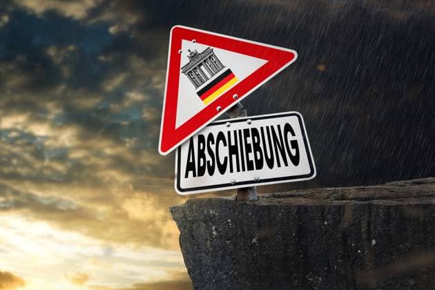 Germany - June 18, 2024: Deportation! Sign on a cliff leaning towards the abyss with Germany flag or colors and Brandenburg Gate. Concept symbolizes criticism of lax deportation in the asylum process. PHOTOMONTAGE *** Abschiebung! Schild auf einer Klippe zum Abgrund geneigt mit Deutschland Fahne bzw. Farben und Brandenburger Tor. Konzept symbolisiert Kritik an lascher Abschiebung im Asyl-Verfahren. FOTOMONTAGE