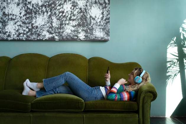 Creative Highlights Symbolbilder A person lounges comfortably on a green sofa, engaging with their smartphone, underneath an abstract artwork, embodying a peaceful smart working environment at home Model Released VictorCuenca_ID22085_646418_022 Copyright: xVictorxCuencax RECORD DATE NOT STATED