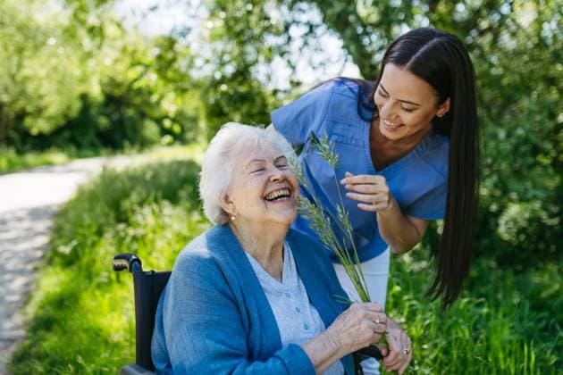IMAGO Creative: Sommer, Sommertage im Stadtpark Female caregiver and senior woman in wheelchair picking wild flowers. Nurse and elderly woman enjoying a warm day in nursing home, public park. Caregiver and senior woman in wheelchair picking wild flowers. Nurse and elderly woman enjoying a warm day in nursing home, public park. model released