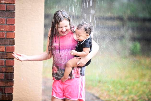 Girl and baby playing in rain, both smiling and enjoying. United States, Florida, Inverness R_YWQX240623D-1468461-01 ,model released, Symbolfoto