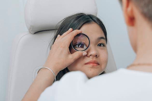 Creative Highlights Symbolbilder Doctor using magnifying glass to examine eye of girl at clinic model released, Symbolfoto property released, ADF00375