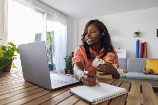 Working mother writing in diary and holding daughter at home office model released, Symbolfoto property released, ALZF00441