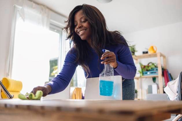 IMAGO Creative, Frühling, Frühjahrsputz Mature woman cleaning table with cleaner at home model released, Symbolfoto property released, ALZF00448
