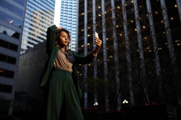 Confident young businesswoman taking selfie through smart phone in front of modern building model released, Symbolfoto, ANNF00997