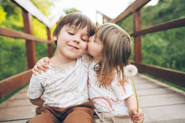 Creative Highlights Symbolbilder Girl kissing boy sitting on wooden bridge at park model released, Symbolfoto, ASVF00038