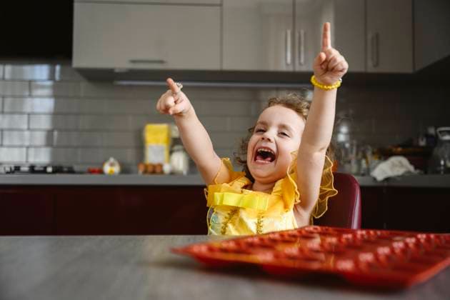 Creative Highlights Symbolbilder Cheerful girl with arms raised enjoying in kitchen at home model released, Symbolfoto property released, EYAF02970
