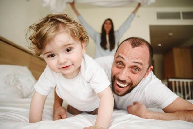 Creative Highlights Symbolbilder Happy father and son lying on bed with mother in background model released, Symbolfoto property released, EYAF03032