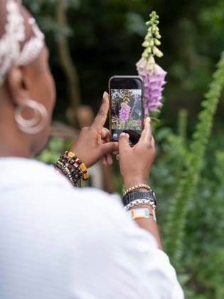 Mature woman photographing flowers in garden model released Copyright: xCulturaxCreativex