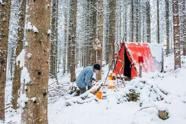 Senior man preparing campfire in snow near tent model released, Symbolfoto, HHF06019