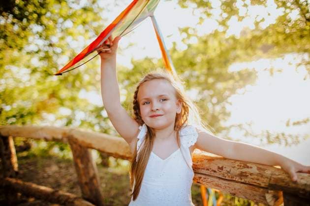 Creative Highlights Symbolbilder Smiling girl with flying kite leaning on fence at garden model released, Symbolfoto property released, MDOF02236