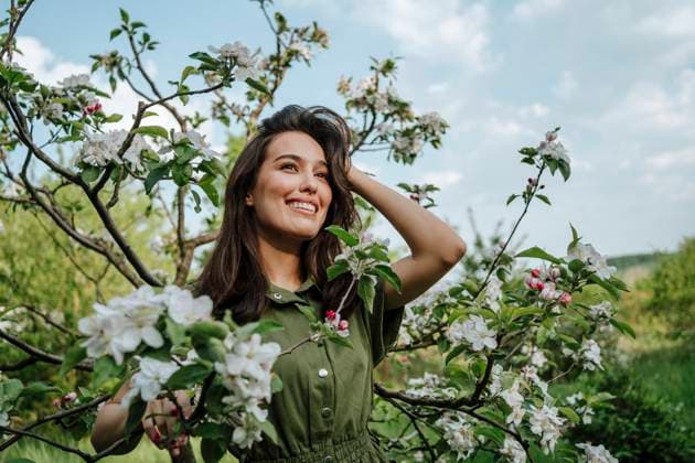 Creative Highlights Symbolbilder Smiling woman standing near apple blossom tree model released, Symbolfoto, MDOF02324