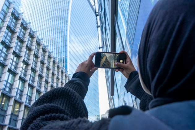 Young woman using phone to take pictures in city model released Copyright: xCCOx