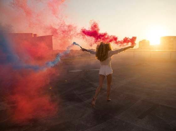 Creative Highlights Symbolbilder Woman holding smoky colored bomb and enjoying sunset model released, Symbolfoto, PNEF03345