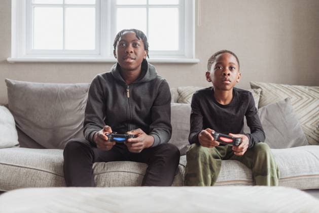 Brothers (10-11), (14-15) playing video game at home model released Copyright: xIko-OjoxMercyxHarunax