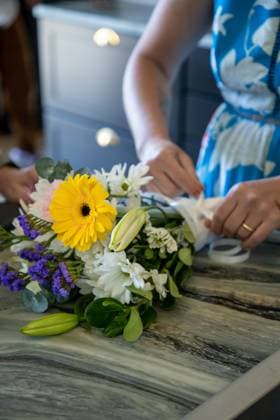 Person arranging a bouquet of colorful flowers on a marble table United States, Washington, Cheney R_XICN240618-1453372-01
