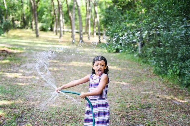 Creative Highlights Symbolbilder Girl playing with a garden hose, spraying water in a backyard. United States, Florida, Inverness CR_YWQX240619-1460796-01 ,model released, Symbolfoto