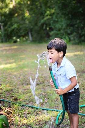 A young boy drinking water from a garden hose in a backyard. United States, Florida, Inverness R_YWQX240619-1460784-01 ,model released, Symbolfoto