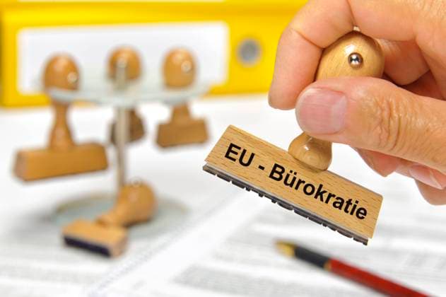 EU-Bürokratie Eine Hand hält einen Holzstempel mit der Aufschrift: EU-Bürokratie *** EU Bureaucracy A hand holds a wooden stamp with the inscription EU Bureaucracy