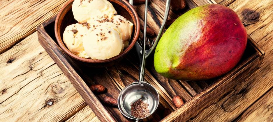 Ice cream with mango flavor. Ice cream, mango fruit and a spoon for ice cream in wooden tray ,model released, Symbolfoto