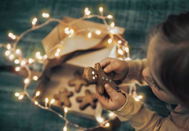 Child Received Gift Box with Christmas Cookies Decorated with Glowing Garland. Little Baby Eating Gingerbread. Happy Winter Holidays.. Kid with Christmas Cookies ,model released, Symbolfoto