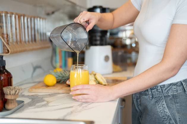 Woman in kitchen, pouring freshly made smoothie, midsection model released Copyright: xCulturaxCreativex
